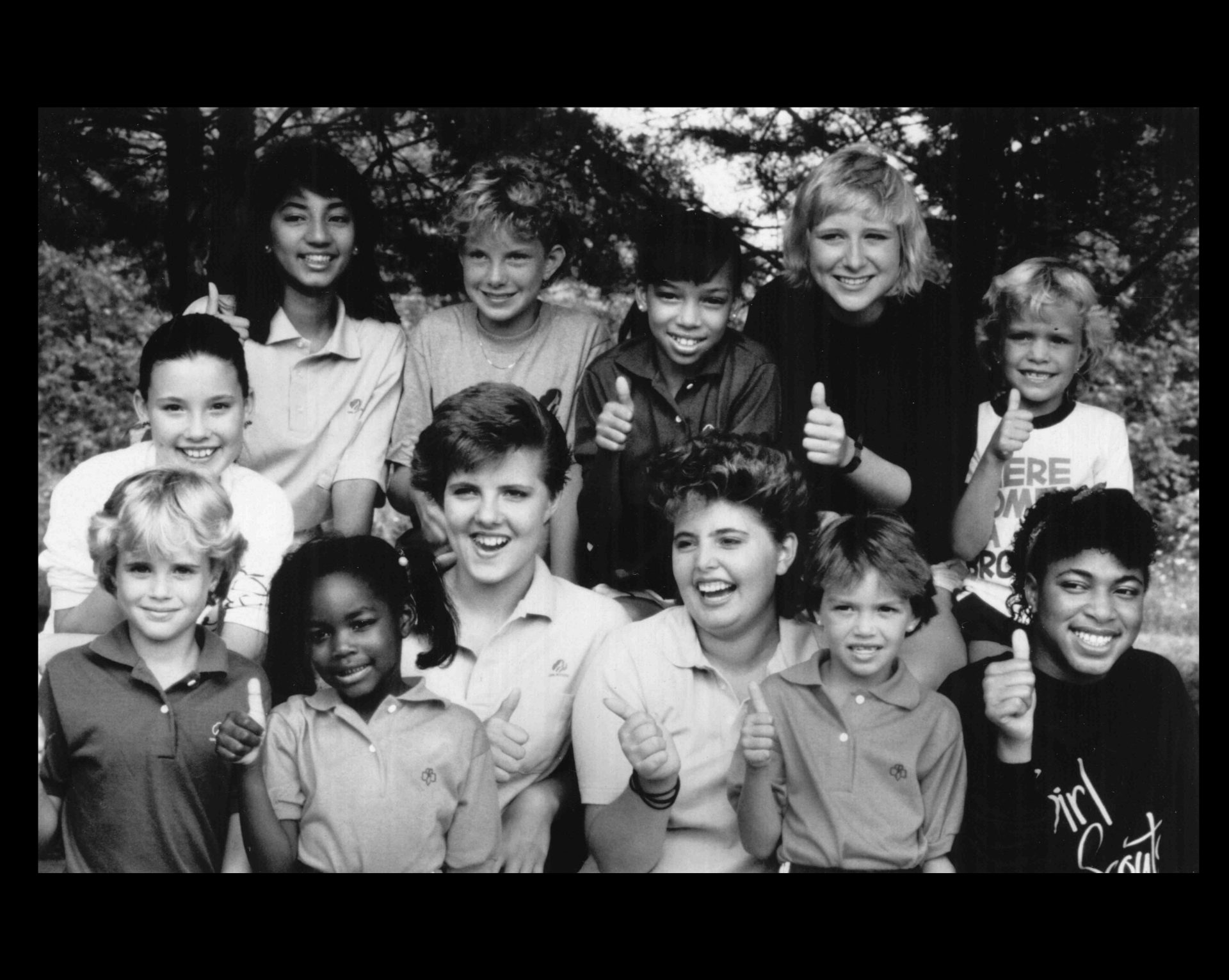 four girl scouts smiling, one is standing, two are kneeling and one is in a wheelchair