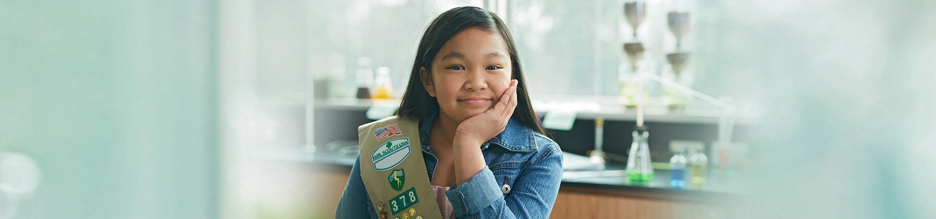  cadette girl scout in sash uniform in school classroom smiling at camera 