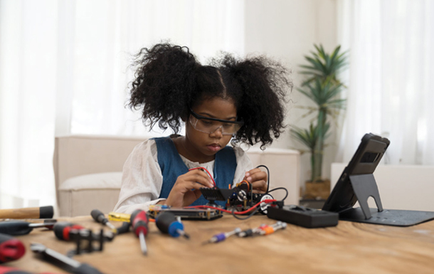 a girl soldering something while watching instructions on a tablet