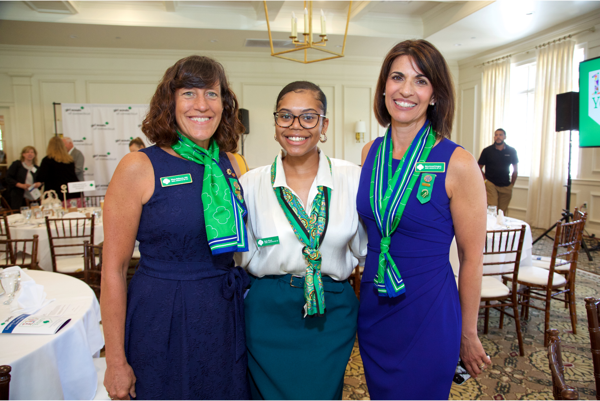 three Girl Scout executives at a banquet standing together smiling